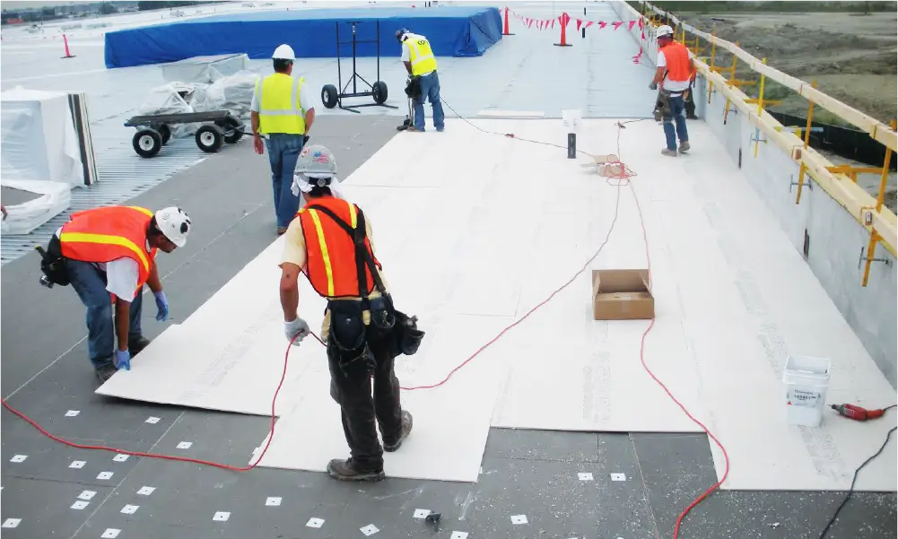 Image of roofers installing insulation boards on a commercial flat roof