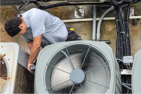 Image of technician working on roof-top HVAC unit