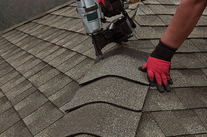 Image of a roofer nailing on ridge cap shingles