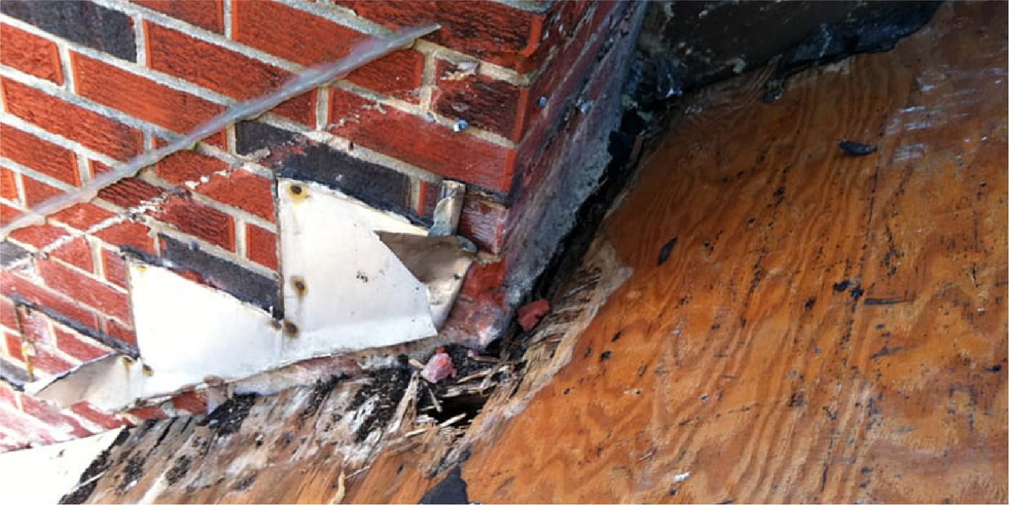 Image of brick chimney with wood rot around it from a roof leak