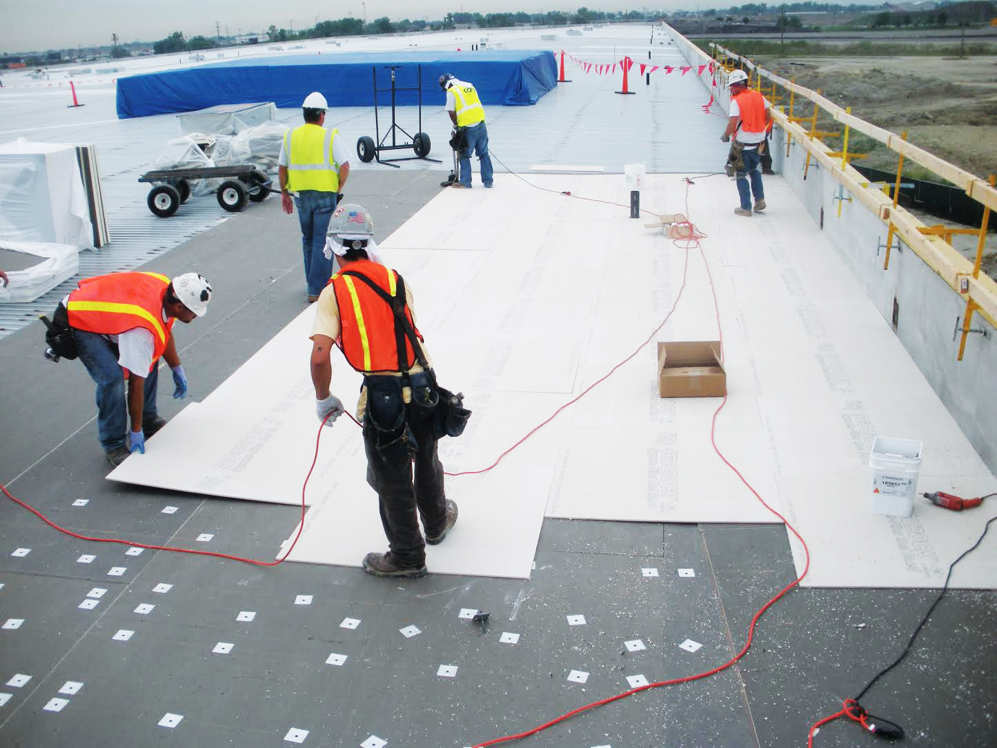 Image of roofers installing insulation boards on a commercial flat roof
