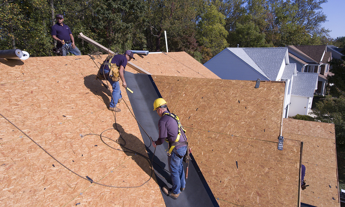 Image of roofing technicians installing leak barrier in the valley of a roof