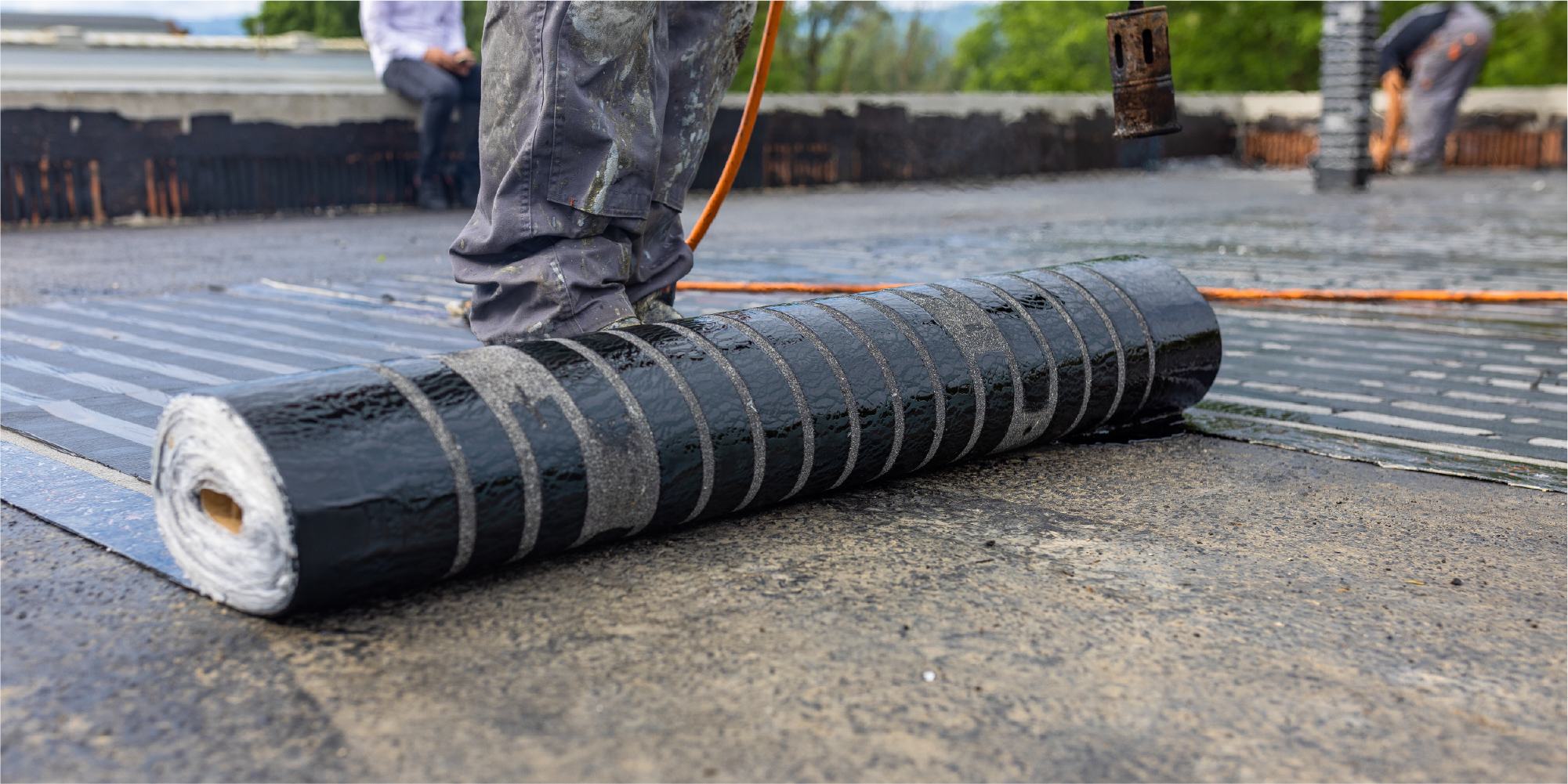 Image of man rolling out modified bitumen roofing on a commercial roof