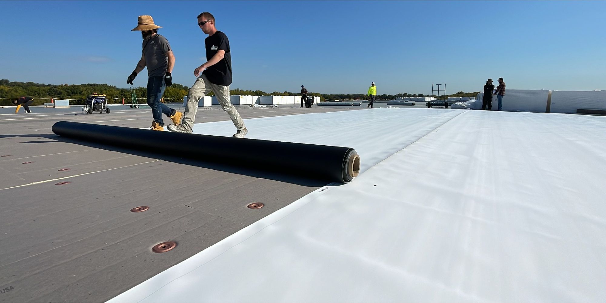 Image of men rolling out single ply roofing on a commercial roof