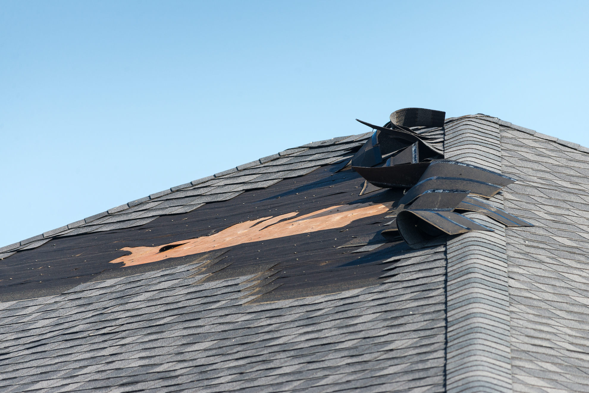 Image of a roof that has had shingles blown off due to wind damage